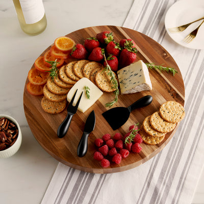 ACACIA WOOD AND METAL CHEESE BOARD SET - Showcasing the natural beauty of acacia wood, our cheese and charcuterie boards have metal feet to elevate them off your table. This round cheese board measures 16″ across and comes with 3 metal cheese tools.