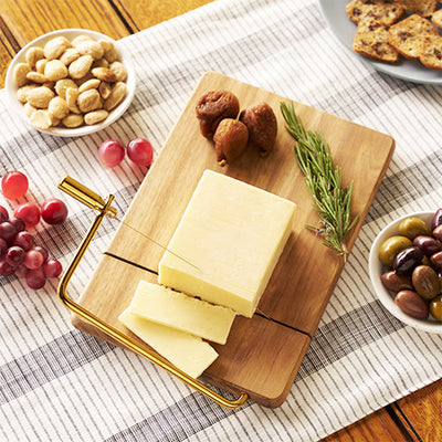 ELEGANT ACACIA WOOD CHEESE BOARD - Upgrade your hors d'oeuvres with this acacia cheese board designed to slice cheeses perfectly every time. A groove in the wooden board guides the built-in wire cheese slicer for perfect rounds of cheddar, stilton, and more.
