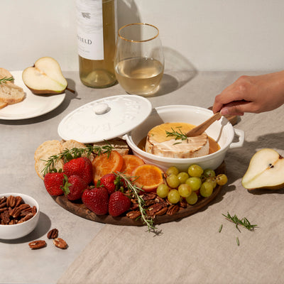 CERAMIC BAKED BRIE DISH - Everybody loves baked brie. This tried and true appetizer just got easier with our stoneware brie baker. Complete with a lid, handles, and an acacia wood spreader for serving, this brie baker is useful and beautiful.
