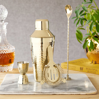 BARWARE ESSENTIALS IN HAMMERED GOLD - Complete with a cobbler style shaker, double jigger, hawthorne strainer, and spoon that doubles as a muddler, this hammered gold stainless steel set includes all the barware essentials and bar tool basics.

