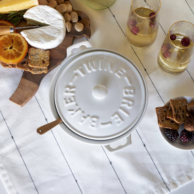 CERAMIC BAKED BRIE DISH - Everybody loves baked brie. This tried and true appetizer just got easier with our stoneware brie baker. Complete with a lid, handles, and an acacia wood spreader for serving, this brie baker is useful and beautiful.
