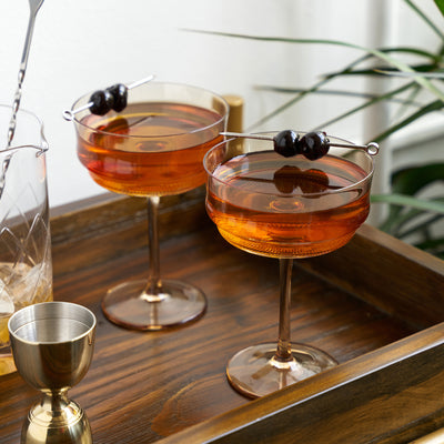 SET OF 2 AMBER TINTED COCKTAIL COUPES - These amber-tinted cocktail glasses bring a golden hue to your favorite beverage. Skip boring clear cocktail tumblers and add some color to your table at your next party with this amber glassware.